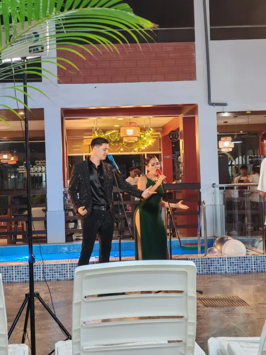 Dúo musical en vivo durante show nocturno al lado de la piscina